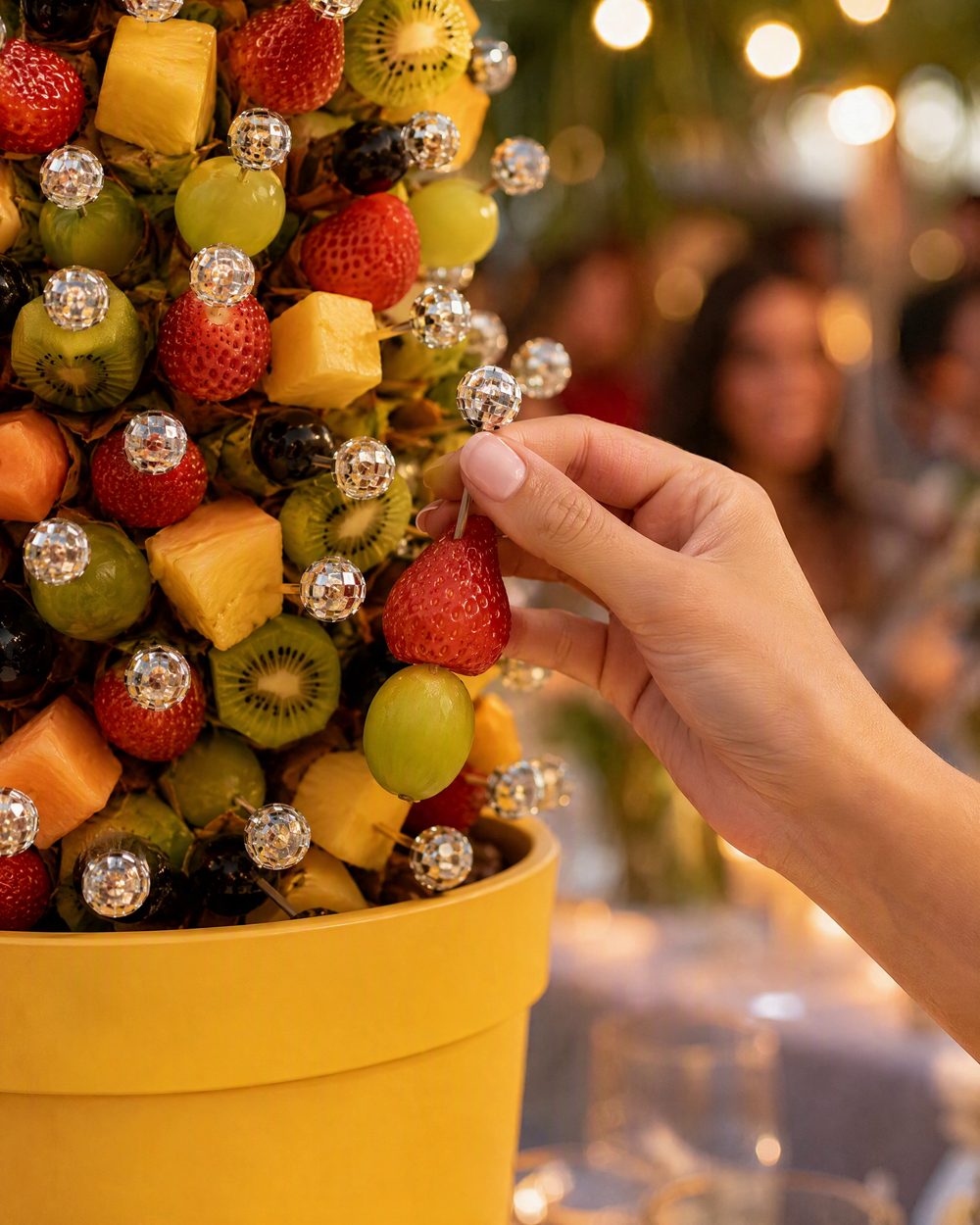 A guest takes a fruit skewer by its silver ball